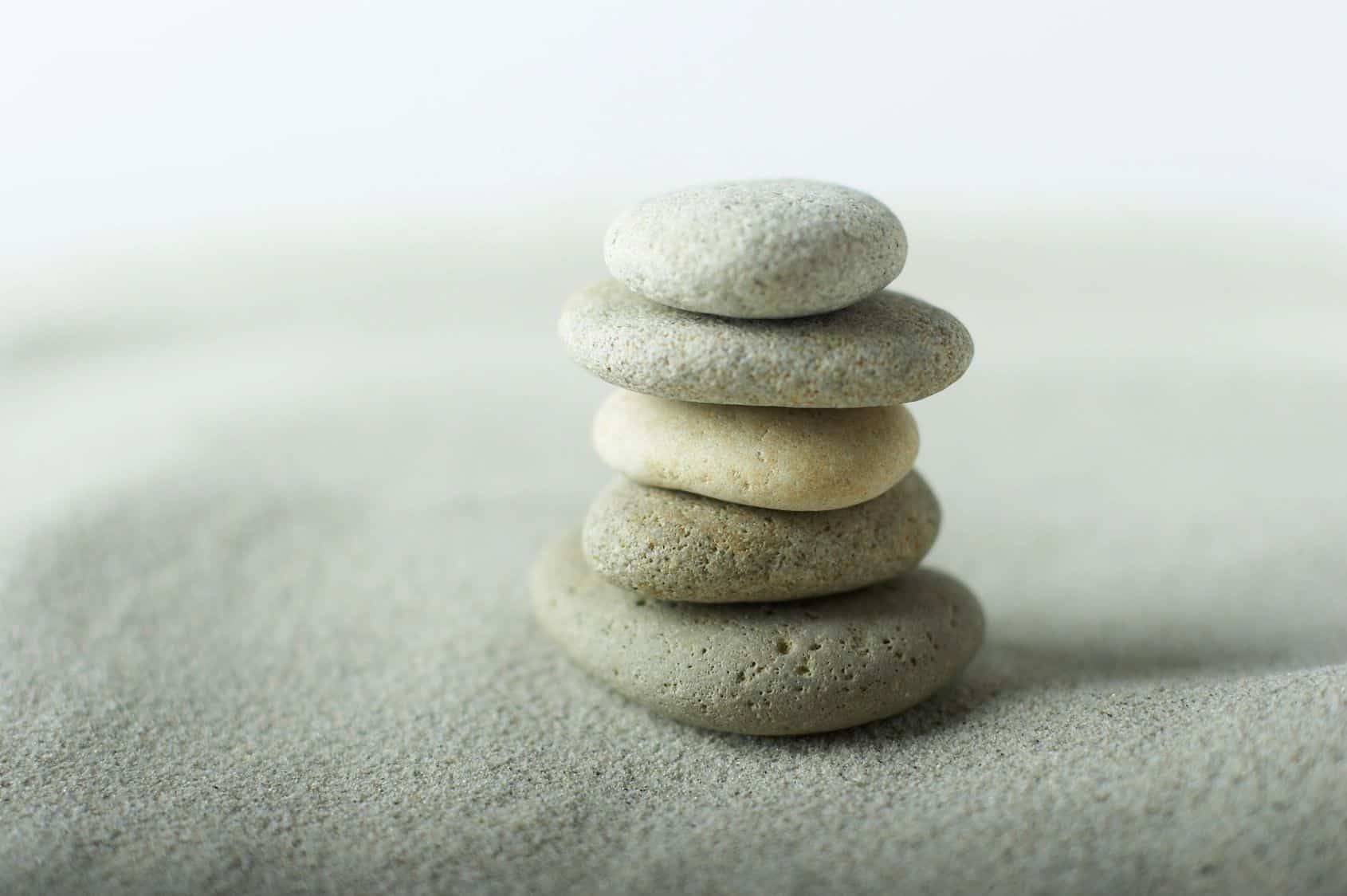 A balanced stack of smooth grey stones on sand